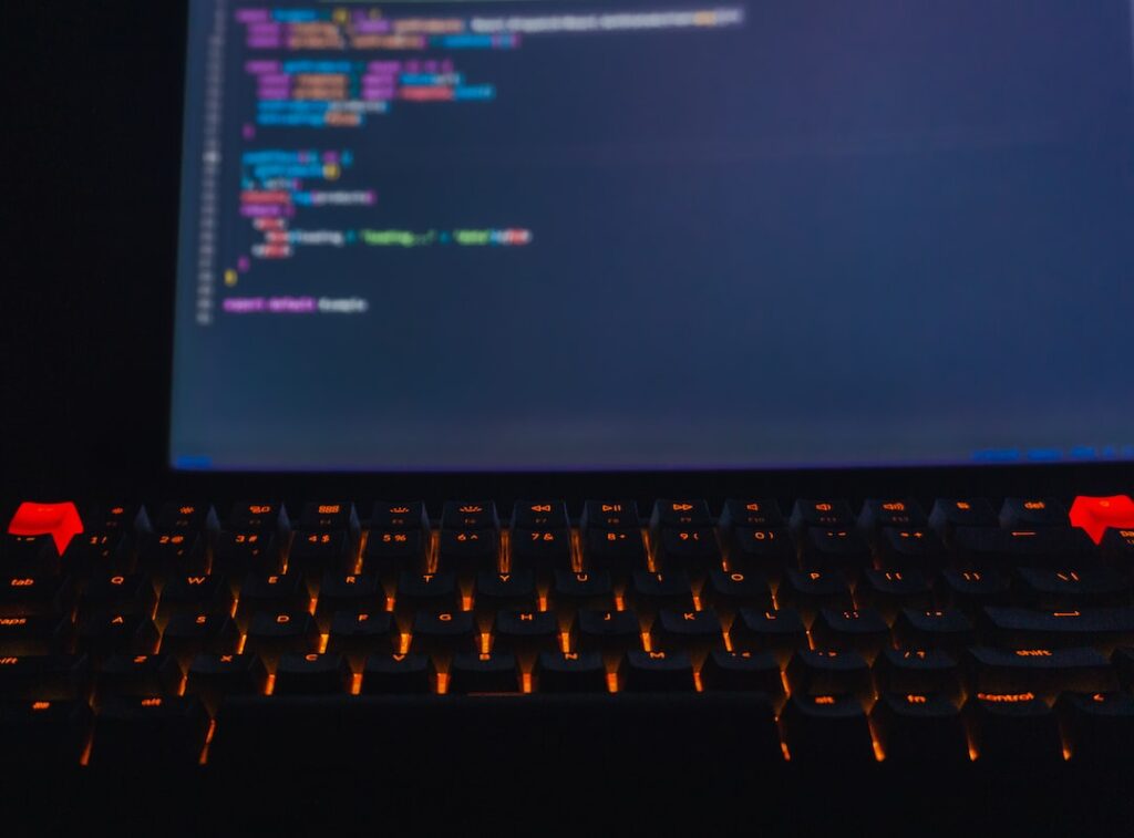 a close up of a keyboard with a computer screen in the background