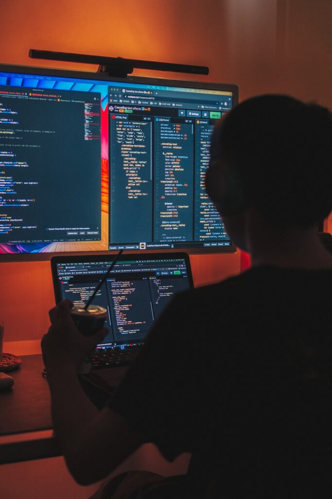 a man sitting in front of two computer monitors