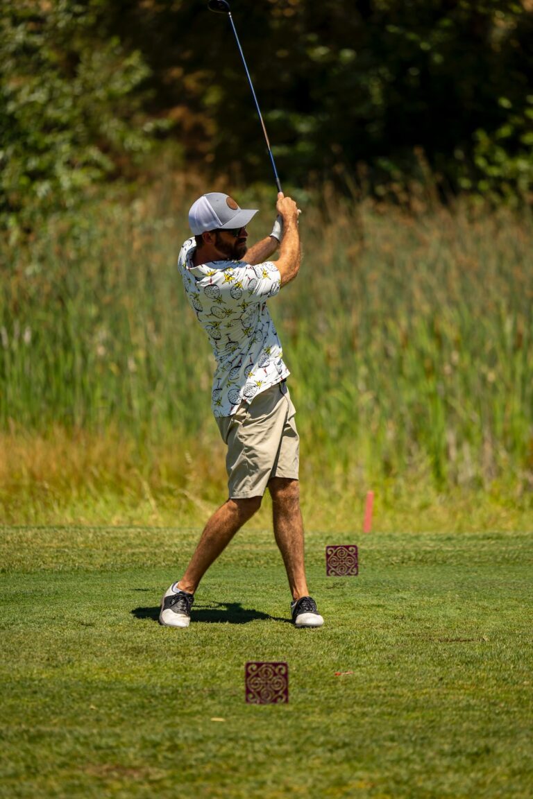 a man swinging a golf club on a lush green field