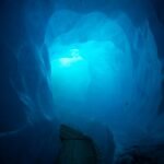 a wooden bench sitting inside of a blue ice cave