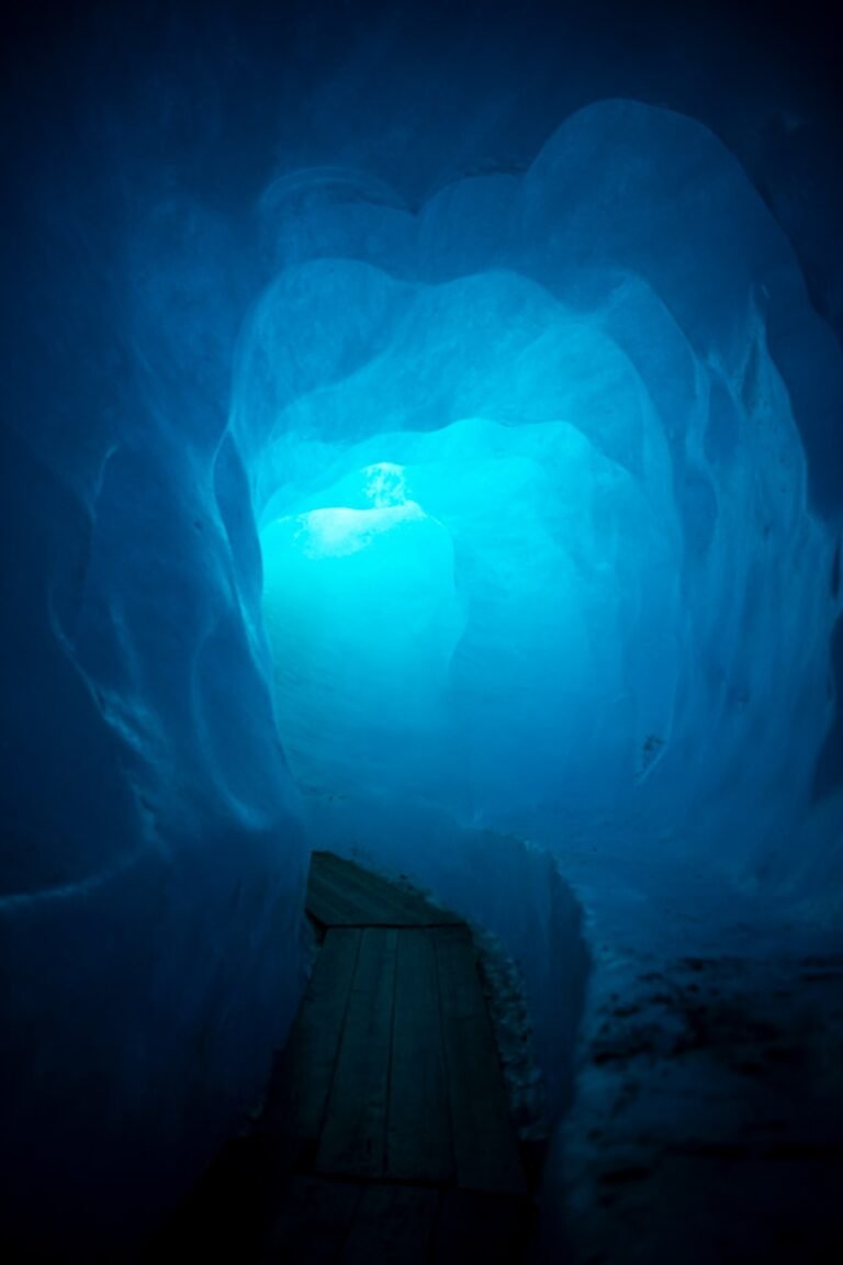 a wooden bench sitting inside of a blue ice cave