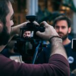 man taking video of standing man wearing black crew-neck top