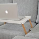 silver MacBook on laptop table on sofa
