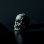 white and black skull figurine on black surface